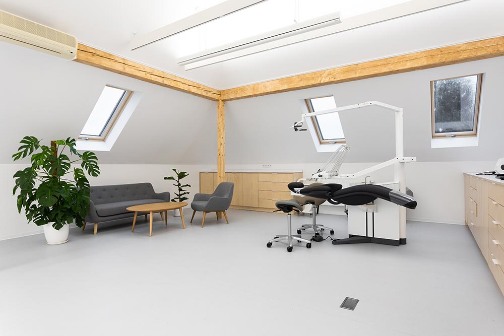 Jasne pomieszczenie z unitem stomatologicznym XO FLEX, zielonymi roślinami i meblami z jasnego drewna