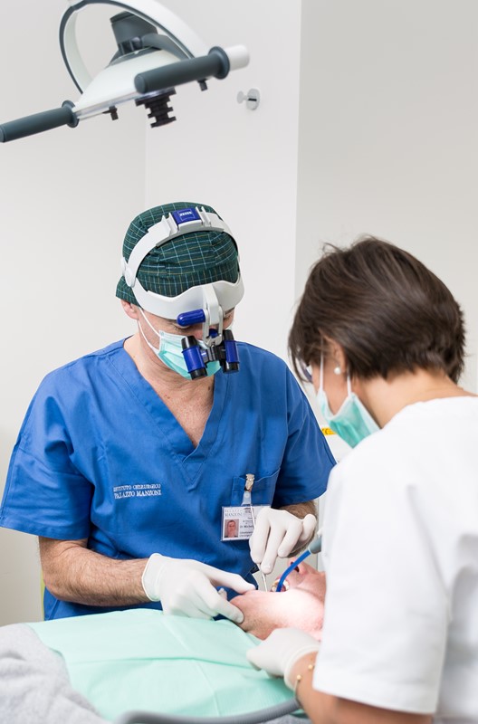 Lekarz dentysta Dr. Michele Jacotti wykonujący zabieg stomatologiczny w lupach