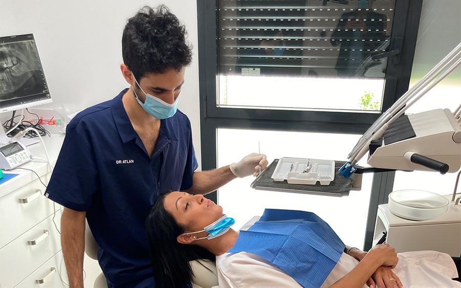 Leworęczny dentysta opracowuje zęba pacjentowi na unicie stomatologiczym XO FLEX. W tle widać białe ściany gabinetu i sprzęt stomatologiczny.